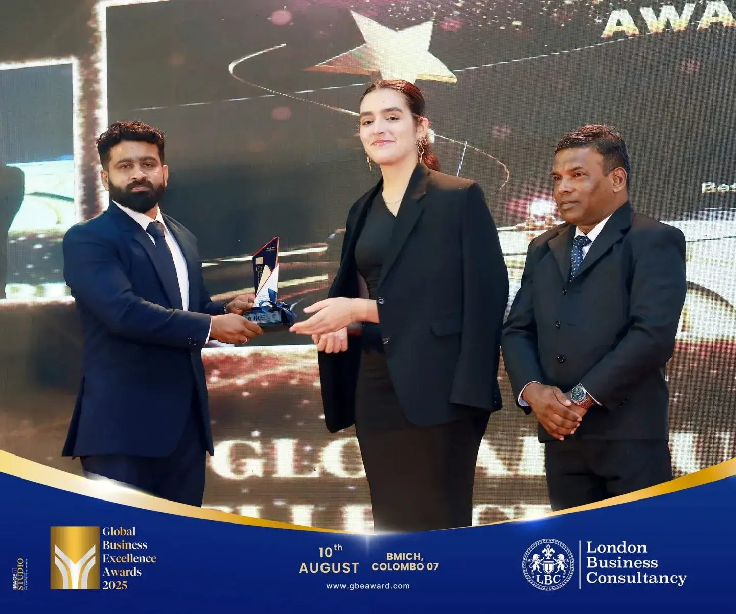 Global Business Excellence Awards recipient accepting a trophy on stage