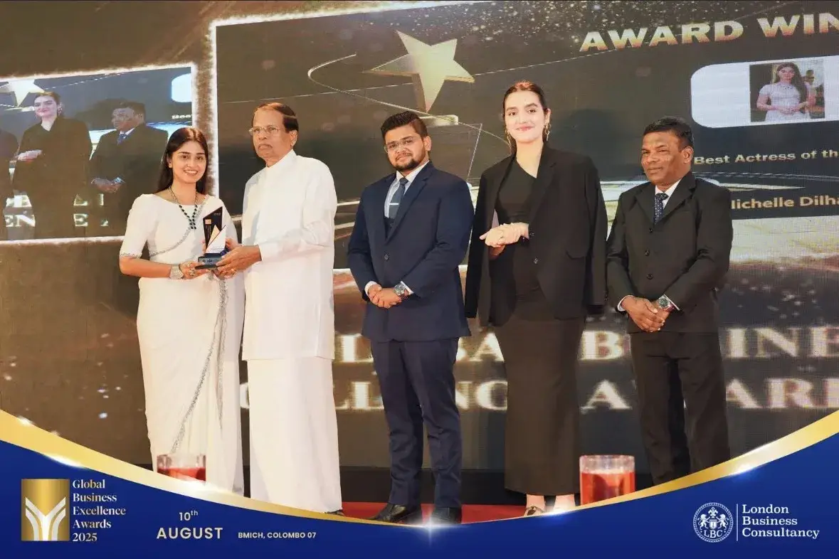 Global Business Excellence Awards recipient receiving a trophy during a stage presentation