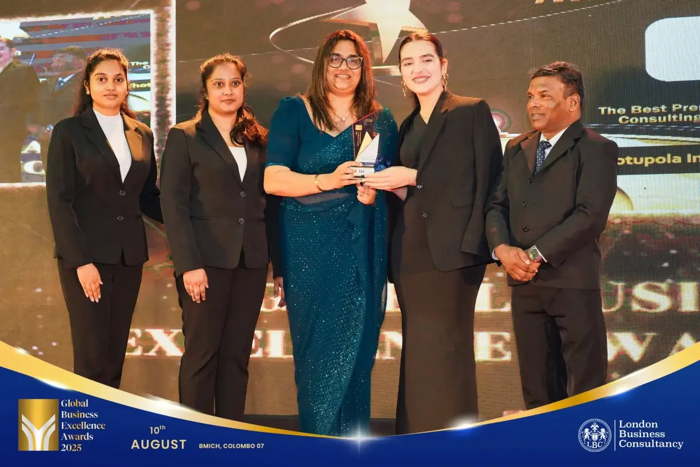 Global Business Excellence Awards recipient and team holding a trophy on stage