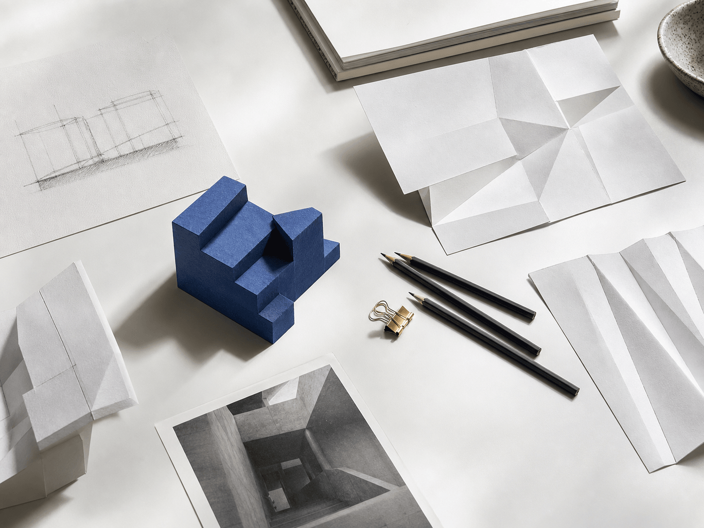 Creative studio table with paper studies and a blue architectural model