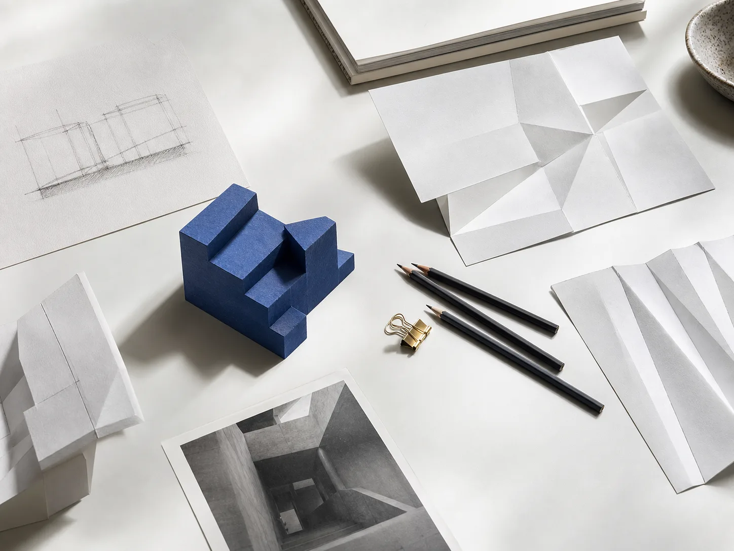 Creative studio table with paper studies and a blue architectural model